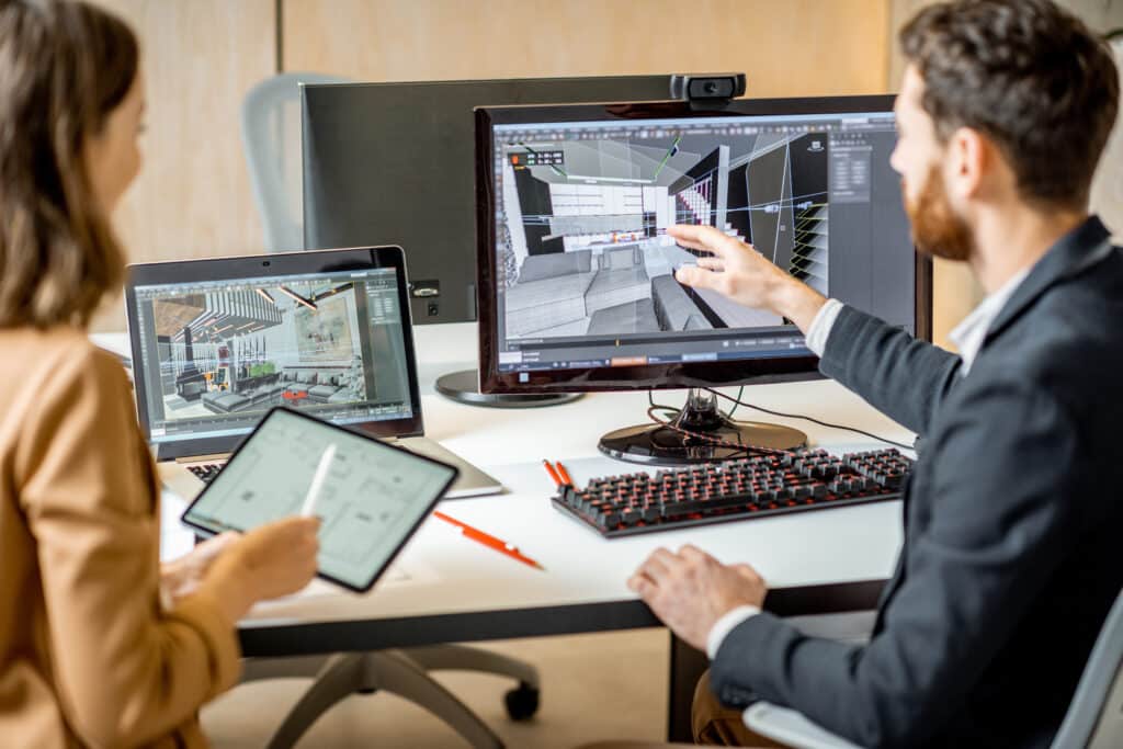Deux employés de bureau créatifs réalisant un design d'intérieur sur ordinateur et tablette numérique dans le bureau moderne d'un cabinet d'architecte. Concept de modélisation 3D et de design d'intérieur numérique
